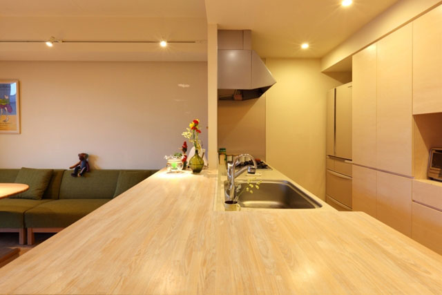 閉じていたキッチンの壁と吊戸棚を撤去して、大きな集成材のカウンターを造作。