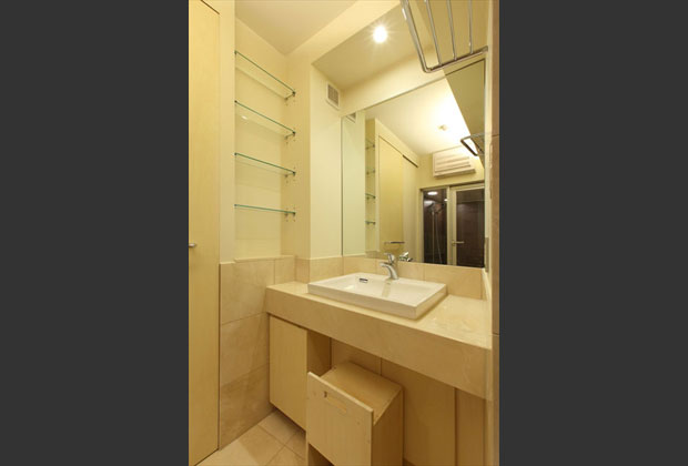 床材と同じ大理石で仕上げた洗面化粧台。大きな鏡、タオル棚、オープン収納なども充実。スツールも造作です。