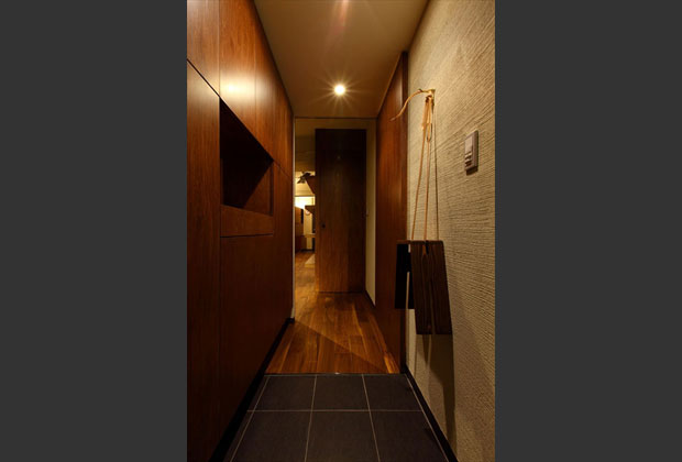 玄関。スリットから左は傘入れなど綿密に計画された収納、右の壁面には玄関で使用するスツールです。