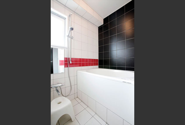 天井に梁があるため、浴室は在来工法に。凹凸タイルやアクセントカラーでインテリア性の高い空間となりました。